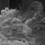 Water, trapped against weir gates, clamouring to move on